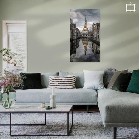 Een foto van de kleurrijke Waag in Alkmaar, met een mooie reflectie in de gracht. Door de huizenrijen aan weerszijden ontstaat een mooie dieptewerking. De huizen in de omgeving heb ik was donkerder gemaakt en de Waag zelf wat lichter. Er hangt wat bewolking boven het gebouw.