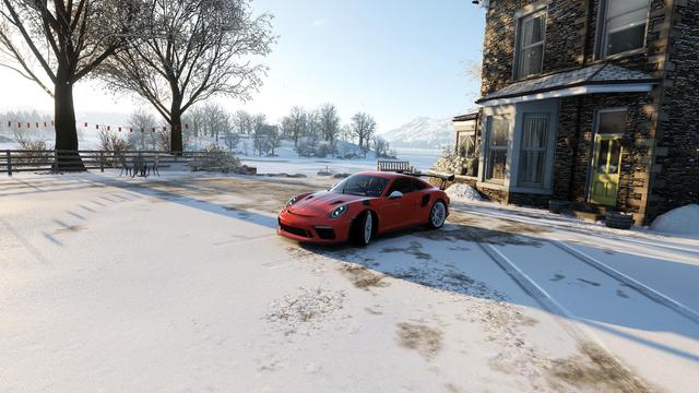 Oranger GT3 vor Haus am See im Schnee (Forza Horizon 4)