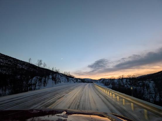 Dämmerungshimmel über der Straße, der Himmel ist klar, nur wenige Wolkenfetzen am Horizont, zusammen mit einem gelben Streifen Restsonnenlicht.