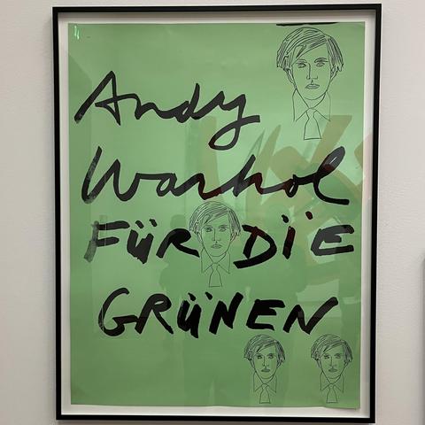 Ein Bild in der Ausstellung „Andy Warhol Keith Haring - Party of Life“  im Museum Brandhorst in München: Einen grünen Hintergrund hat Warhol mit dem schwarzen Schriftzug „Andy Warhol FÜR DIE GRÜNEN“ und mehreren kleinen gezeichneten einfarbigen Selbstportraits versehen.
