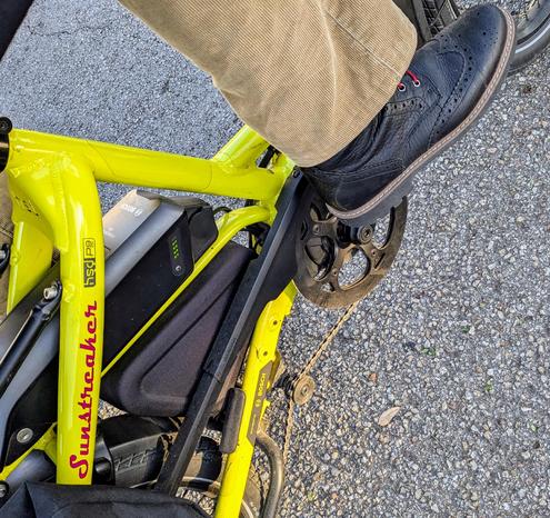 A photo of my right foot on the pedal of a 

yellow Tern HSD cargo bike with its name, Sunstreaker, in red on the seat stay

I'm wearing

black wingtip boots with red laces under a tsn corduroy pantleg