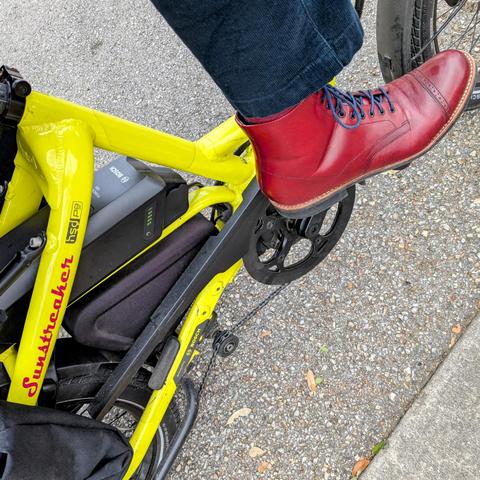  A photo of my right foot on the pedal of a 

yellow Tern HSD cargo bike with its name, Sunstreaker, in red on the seat stay

I'm wearing

Red captoe boots with blue laces under a navy blue pantleg
