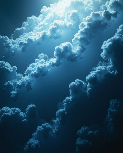A surreal view of fluffy, white clouds illuminated by soft blue light, layered in an expansive, dreamlike atmosphere. The scene captures the depth and texture of towering cloud formations in a calm, ethereal environment.