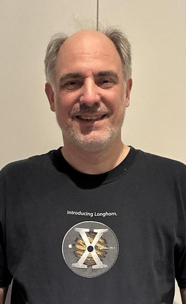 A picture of me, an old white man with little hair and a grey beard stubble. 
Wearing a Black T-Shirt "Introducing Longhorn" and a Mac OS X Tiger Logo