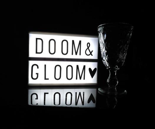 Kleine Lightbox mit Do-It-Yourself-Message, die besagt: Doom & Gloom – plus ein schwarzes Herzchen. Neben der Lightbox steht ein festliches Kristallglas.