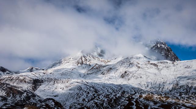 Panorámica a color donde se ve parte de los picos del Peyreget y Midi d'Ossau entre nubes y con sus faldas nevadas.