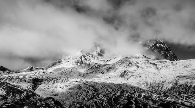 Panorámica en blanco y negro donde se ve parte de los picos del Peyreget y Midi d'Ossau entre nubes y con sus faldas nevadas.