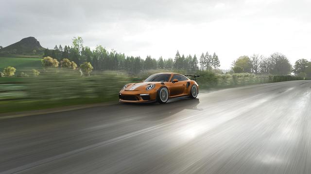 oranger Porsche GT3 auf regennasser Fahrbahn bei leichtem Regen