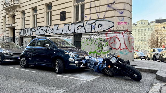 Anwohnerparkplatz: Eine schwarze Kawasaki 1100 ist umgekippt. Das hat eine hellblaue Vespa mitgerissen, welche wiederum gegen einen kleinen schwarz-bläulichen Fiat gekippt ist.