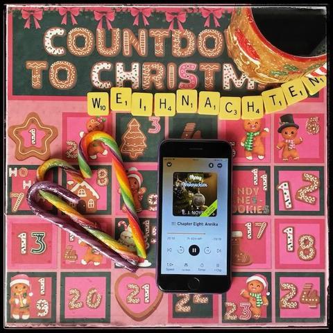An iPhone with the cover of Merry Weihnachten by E. J. Noyes, narrated by Abby Craden, next to a couple of rainbow candy canes and a gingerbread man mug. The background is a pinkish countdown to Christmas, with various drawings, and below the word "Christmas", Scrabble letters spelling "Weihnachten".