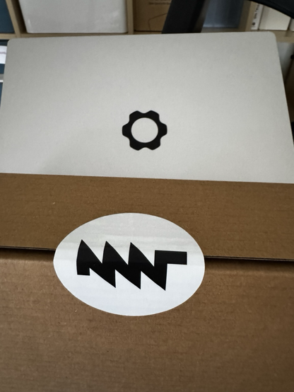 Box with MNT log in the forefront with Framework laptop logo in the background.