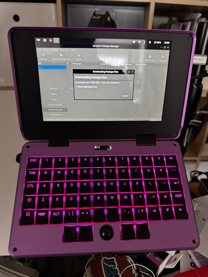 Purple MNT Pocket Reform, open and booted up with packages updating on screen.