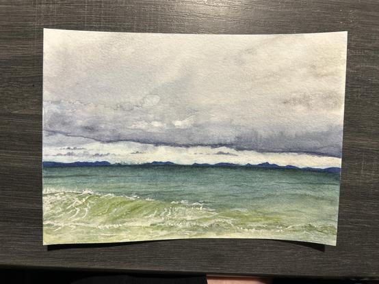 A seascape with stormy clouds (currently very pale, but blue-gray and periwinkle) and small dark clouds near the horizon. There are small dark blue islands all along the horizon. The water is dark teal, fading to a light green towards the foreground. Emphasis is placed on the splashes to the best of my ability!
