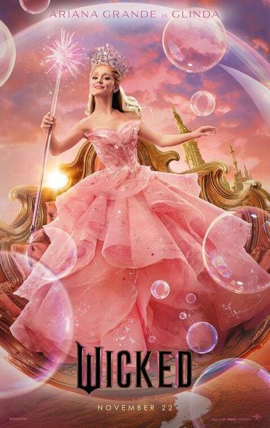 Filmposter van Wicked met heel veel roze. Ariana Grande in een grote roze baljurk met grote transparante toverstaf, luchtbelletjes die in het rond zweven, op de achtergrond de contouren van een gouden troon en verderop die van een eveneens gouden kasteel. Een opkomende (of ondergaande) zon verschuilt achter Ariana.