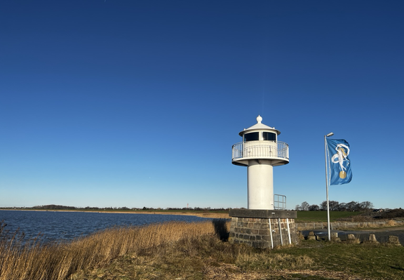 Leuchtfeuer und Fahnenmast mit Fahne vor strahlend blauem Himmel, Glückstadt, Nordermole