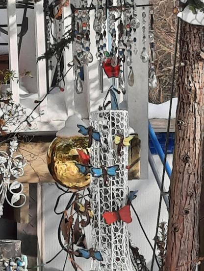 White wire basket with butterflies and dragon flies.  A beaded chandelier overlooks.  A gold ball hangs near
