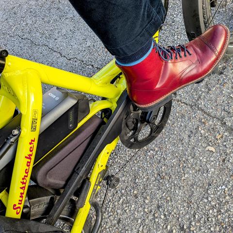 A photo of my right foot on the pedal of a 

yellow Tern HSD cargo bike with its name, Sunstreaker, in red on the seat stay

I'm wearing

red captoe boots with navy blue laces under a navy blue corduroy pantleg