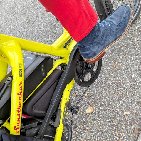 A photo of my right foot on the pedal of a 

yellow Tern HSD cargo bike with its name, Sunstreaker, in red on the seat stay

I'm wearing

blue suede moc toe boots with light blue laces under a vivid red pantleg