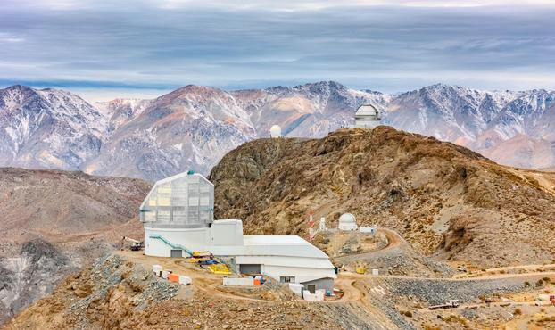A photography of the NSF–DOE Vera C. Rubin Observatory, jointly funded by the U.S. National Science Foundation (NSF) and the U.S. Department of Energy (DOE) Office of Science, seen here on the low ridge of Cerro Pachón in Chile with snow-dusted mountains in the background. With an altitude of more than 2600 meters (8600 feet) at Rubin Observatory, Cerro Pachón is an ideal location for astronomical research with its dry, stable air. The 8.4-meter Simonyi Survey Telescope at Rubin Observatory, equipped with the LSST Camera — the largest digital camera in the world — will survey the entire southern hemisphere every few nights for a decade to create an ultra-wide ultra-high-definition time-lapse record of our Universe. This unique ‘movie’ will bring the night sky to life, yielding a treasure trove of discoveries.

Rubin is positioned near two other observatories in the foothills of the Chilean Andes: the Gemini South telescope, seen at upper-right, and the SOAR Telescope, the smaller telescope to Gemini’s left. Gemini South is one half of the International Gemini Observatory, supported in part by the U.S. National Science Foundation and operated by NSF NOIRLab. The small dome directly to the right of Rubin is the Rubin Auxiliary Telescope (AuxTel), which will provide complementary data on the atmosphere above to assist Rubin’s observations of the Universe.