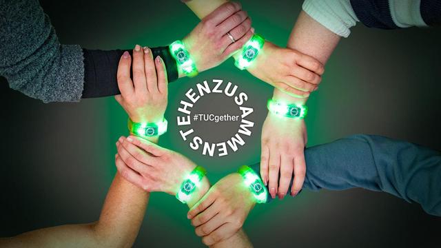 Ineinandergreifende Hände mit dem Leuchtarmbändchen