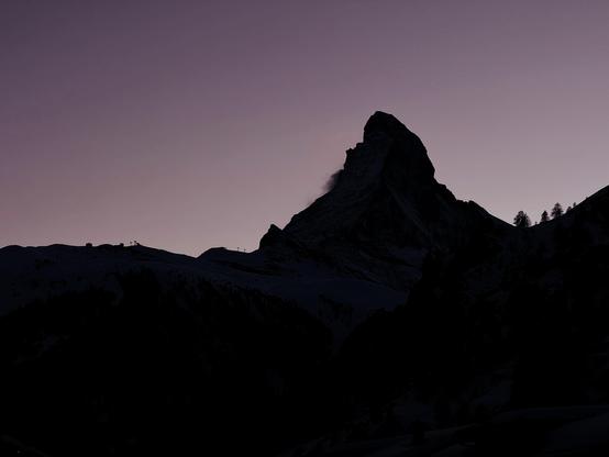 Silhouette of the Matterhorn on a washed out purple sky