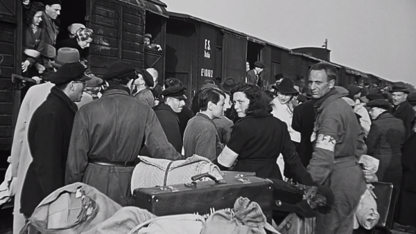zwart-wit foto van een van de NS-transporten in de Tweede Wereldoorlog, deportaties vanuit Westerbork naar de vernietigingskampen.
Goederenwagons met op het perron veel oorlogsslachtoffers die op het punt staan gedeporteerd te worden.