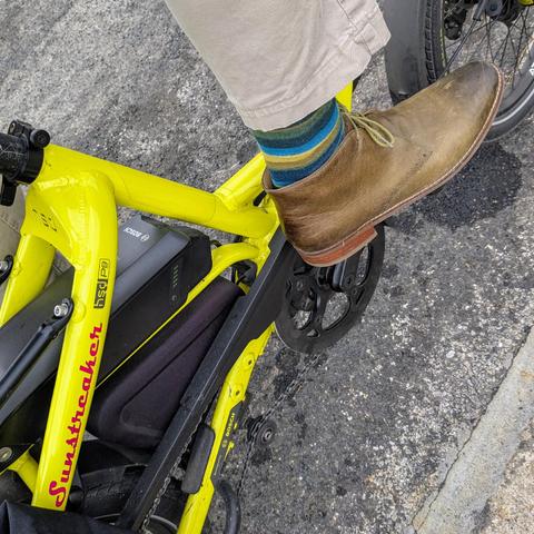 A photo of my right foot on the pedal of a 

yellow Tern HSD cargo bike with its name, Sunstreaker, in red on the seat stay

I'm wearing

olive ankle boots under a khaki blue pantleg
