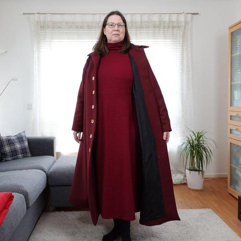 Woman in a red coat, full body image, the coat is open and shows a black lining