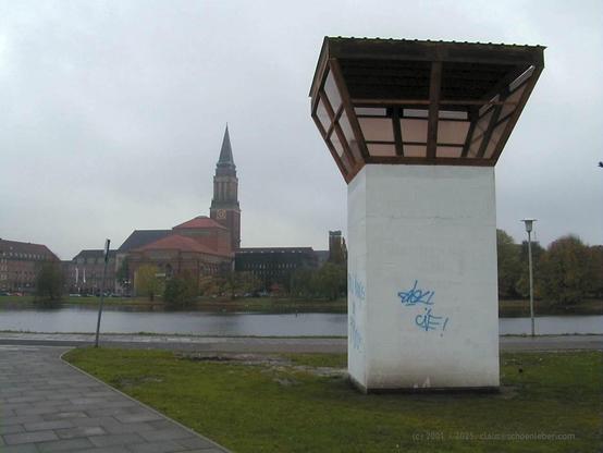 In Kiel steht vor der Kulisse des Rathausturms als Kunstprojekt für kurze Zeit ein Wachturm. Er besteht aus einem ca. 5m hohen aufrecht stehenden Quader mit quadratischem Grundriss in Weiß und darauf aufgesetzt der verglaste Wachraum aus braunem Holz in Form einer auf dem Kopf stehenden Pyramide ohne Spitze, so dass die Fenster auch die Sicht nach unten freigeben. 

Der weiße Sockel weist Graffiti in blauer Schrift auf.

Das Projekt fand im Jahre 2001 statt, das Foto ist vom 11. November jenes Jahres.
