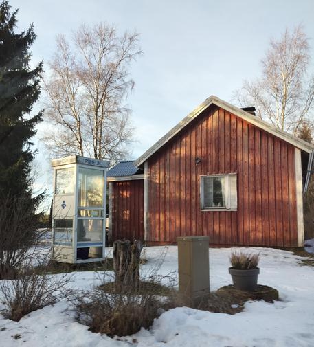 A old wooden house has an old phone booth in the yard 