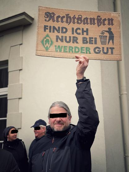 Ein Mann hält ein Pappschild mit der Aufschrift „Rechtsaußen find ich nur bei Werder gut“ in die Höhe. 