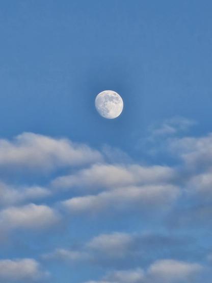 photo of the moon and clouds during daytime against blue sky.