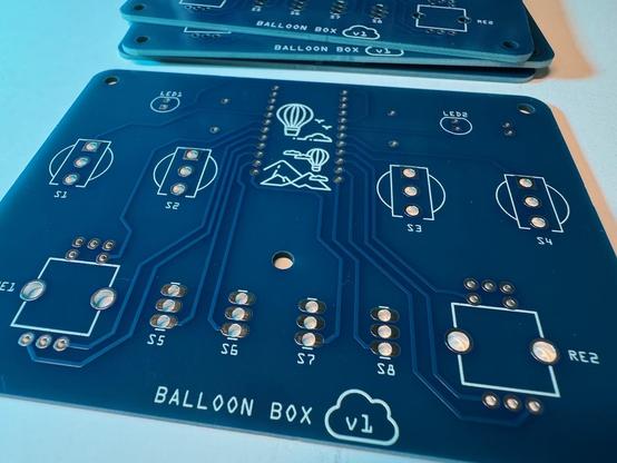 A blue circuit board with white lettering that outlines the positions of various components. The words Ballon Box v1 are at the bottom. 