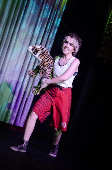Austin Tacious, still dressed as Rocky, this time holding a tiger plushy that's about as big as his whole torso.