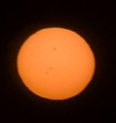 Handyfoto der Sonne, dunkelorange, mit deutlich erkennbaren Sonnenflecken