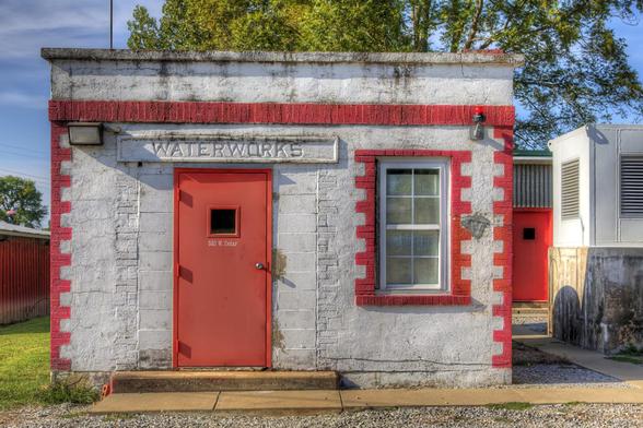 A small, rectangular building with a white and red facade houses the entrance marked "Waterworks" above the red door. 