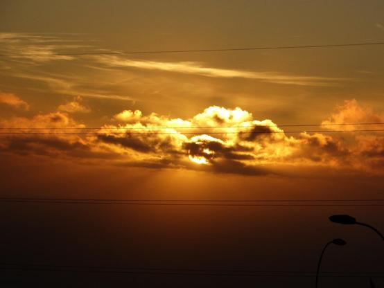 Atardecer naranja. El sol se esconde entre las nubes.