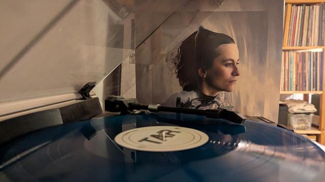Die Vinyl liegt auf dem Plattenspieler, im Hintergrund sieht man das Albumcover