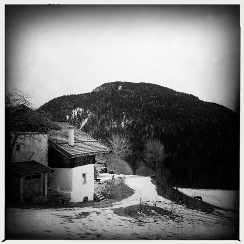 Un maso montano ed un prato innevato. Il bosco di una montagna sullo sfondo