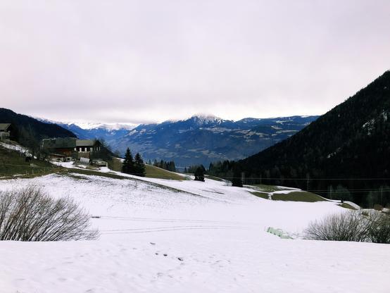 An open space in the mountains covered by snow and mountain peaks in the distance