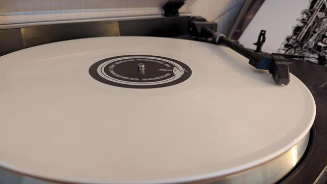 Die Vinyl liegt auf dem Plattenspieler und ist opak weiß