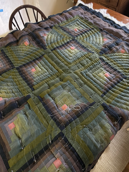 Purple and green quilt in the process of being hand quilted with a radiating leaf design