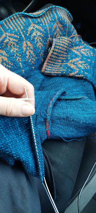 Knitting project showing stranded colourwork in copper coloured yarn on blue green main colour