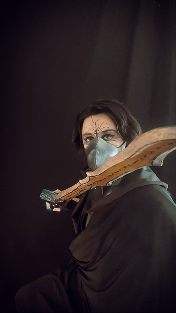 A man holding a hand crafted sword (made with eva foam) and looking at camera (pose 2).