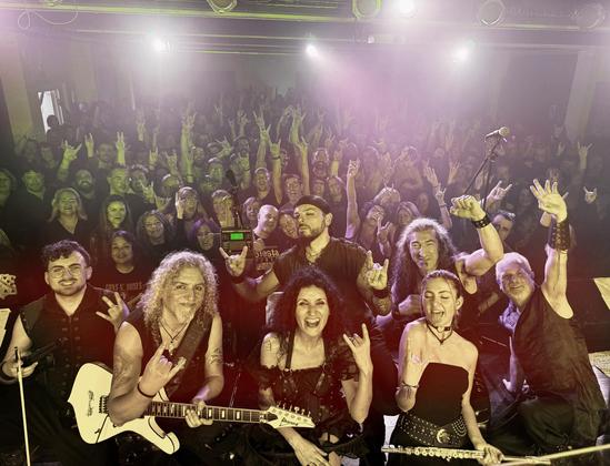 Foto final de concierto en el Foment Martinenc con la banda Leyendärian en primer plano en el escenario y el público llenando la sala en segundo plano.