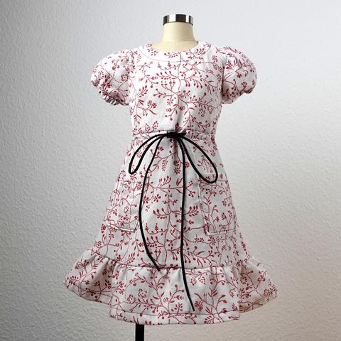 A white dress with red flowers print, puffy sleeves and ruffles on the skirt and a drawstring waist