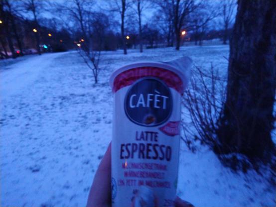 ice coffee from netto supermarket in foreground, snowy park in the back. to the right is a tree, approximately 1meter away from the camera 
