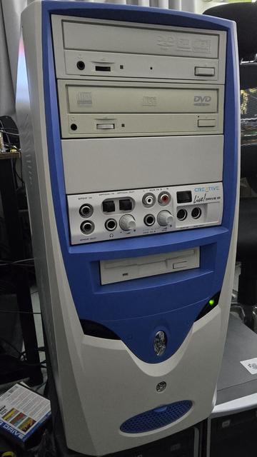 Retro beige and blue PC tower with a Creative Live! Drive IR front panel. The case features two optical drives, a floppy drive, and the Live! Drive IR module, which includes various audio input/output ports such as SPDIF, optical, RCA, MIDI, and microphone inputs. A green LED indicator is lit on the front panel.