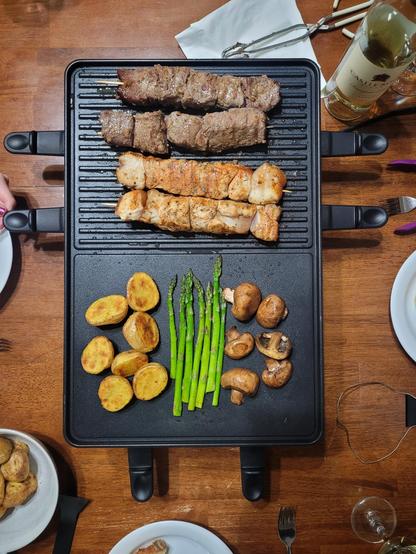 A raclette dinner with beef, chicken, asparagus, potatoes and mushrooms. 