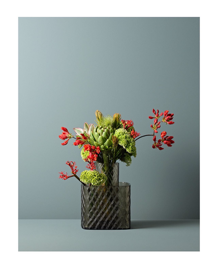 Dieses Foto zeigt eine Vase von Ligne Roset mit einem wunderschönen Blumen-Arrangement auf einer schlichten Farbfläche.